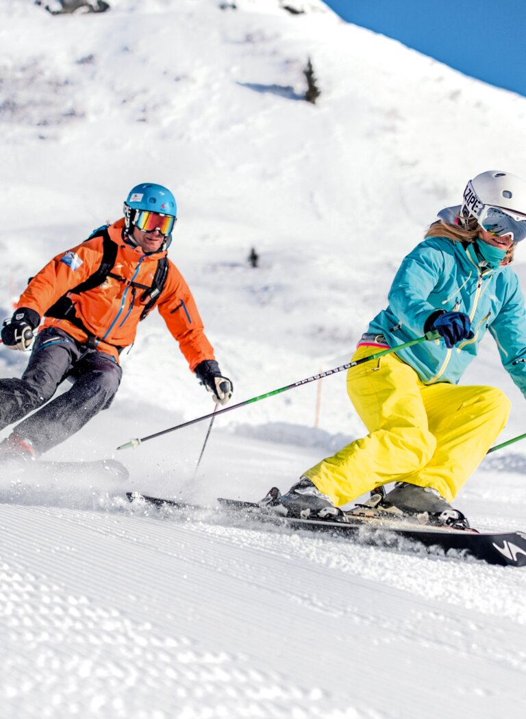 Zwei Skifahrer carven bei Sonnenschein über breite, frisch präparierte Piste mit Pulverschnee. | © Gasteiner Bergbahnen AG
