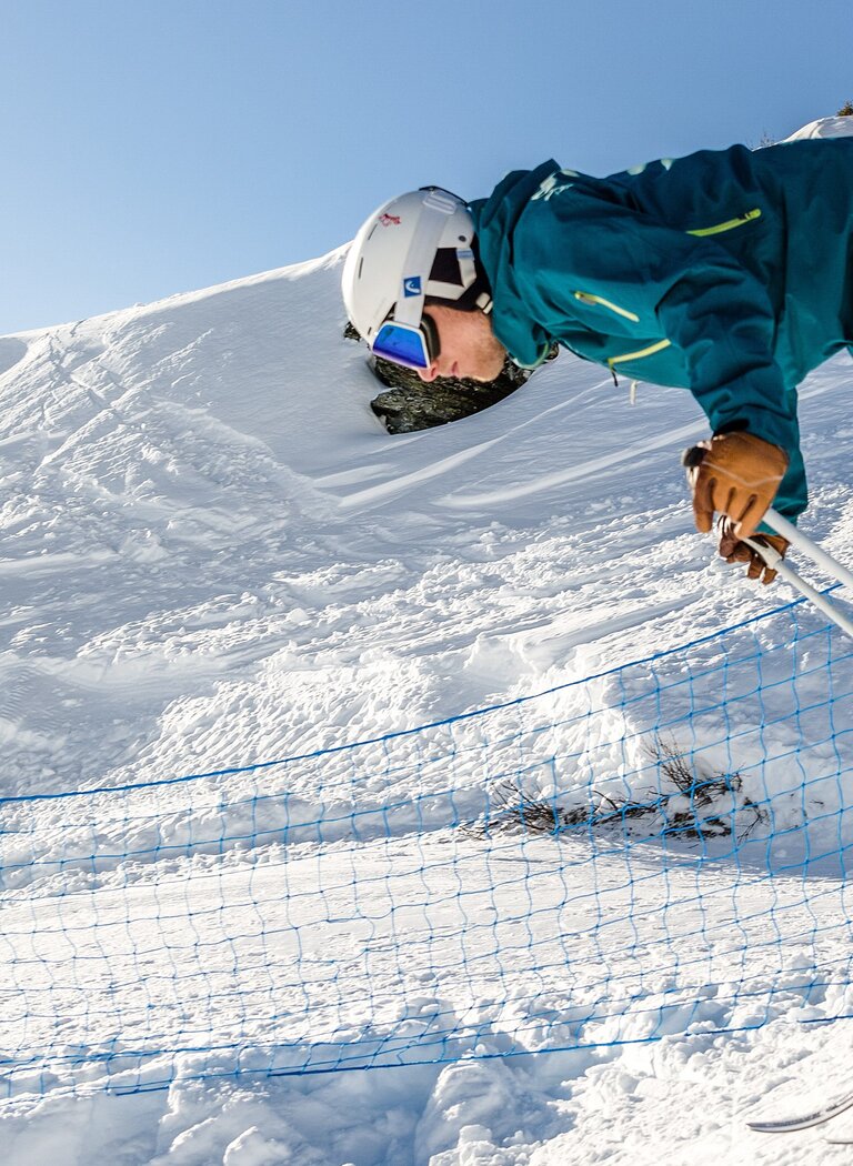 Skifahrer stößt sich vom Starttor auf verschneiter Piste ab, bereit für die Abfahrt bei Sonnenschein. | © Gasteiner Bergbahnen AG
