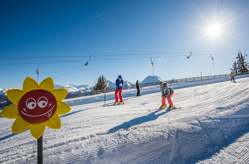 Child skis on funslope with colorful sun marker in bright sunshine and mountain view. | © Tourismusverband Großarltal