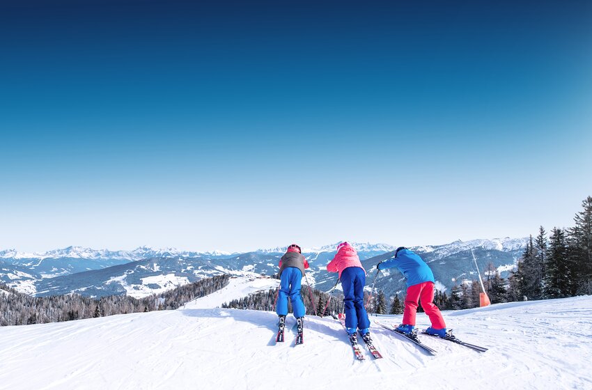 Drei Kinder starten beim Skifahren in Ski amadé ins Tal | © Ski amadé GmbH Drei Kinder am Startpunkt einer Skipiste, bereit zur Abfahrt mit Blick über verschneite Berge in Ski amadé. | © Ski amadé GmbH