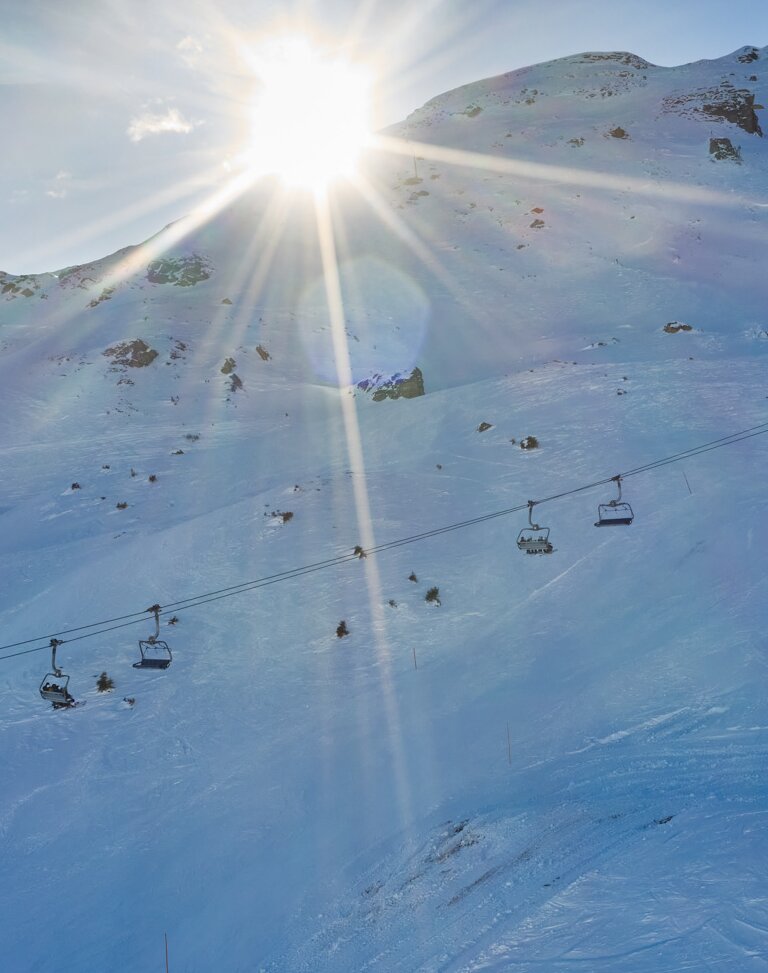 Chairlift moves over snowy slope with funpark in low morning sunlight | © Gasteiner Bergbahnen AG